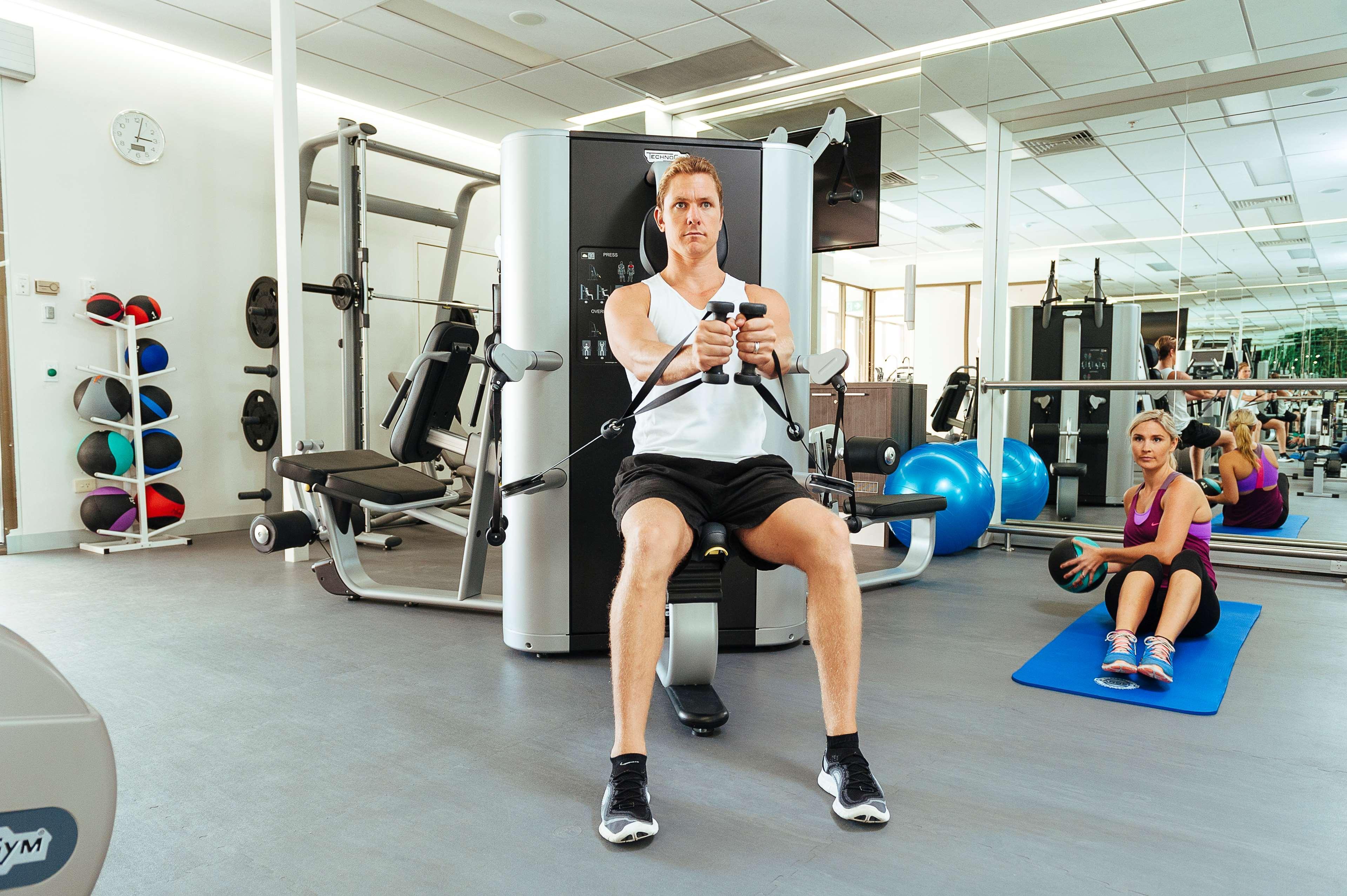 Stamford Plaza Adelaide Hotel ภายนอก รูปภาพ The photo shows a gym setting with two individuals engaged in workout activities. 

In the foreground, a man is seated on a machine, using the handles to perform a rowing exercise. He is wearing a sleeveless shirt and shorts, indicating an active wor