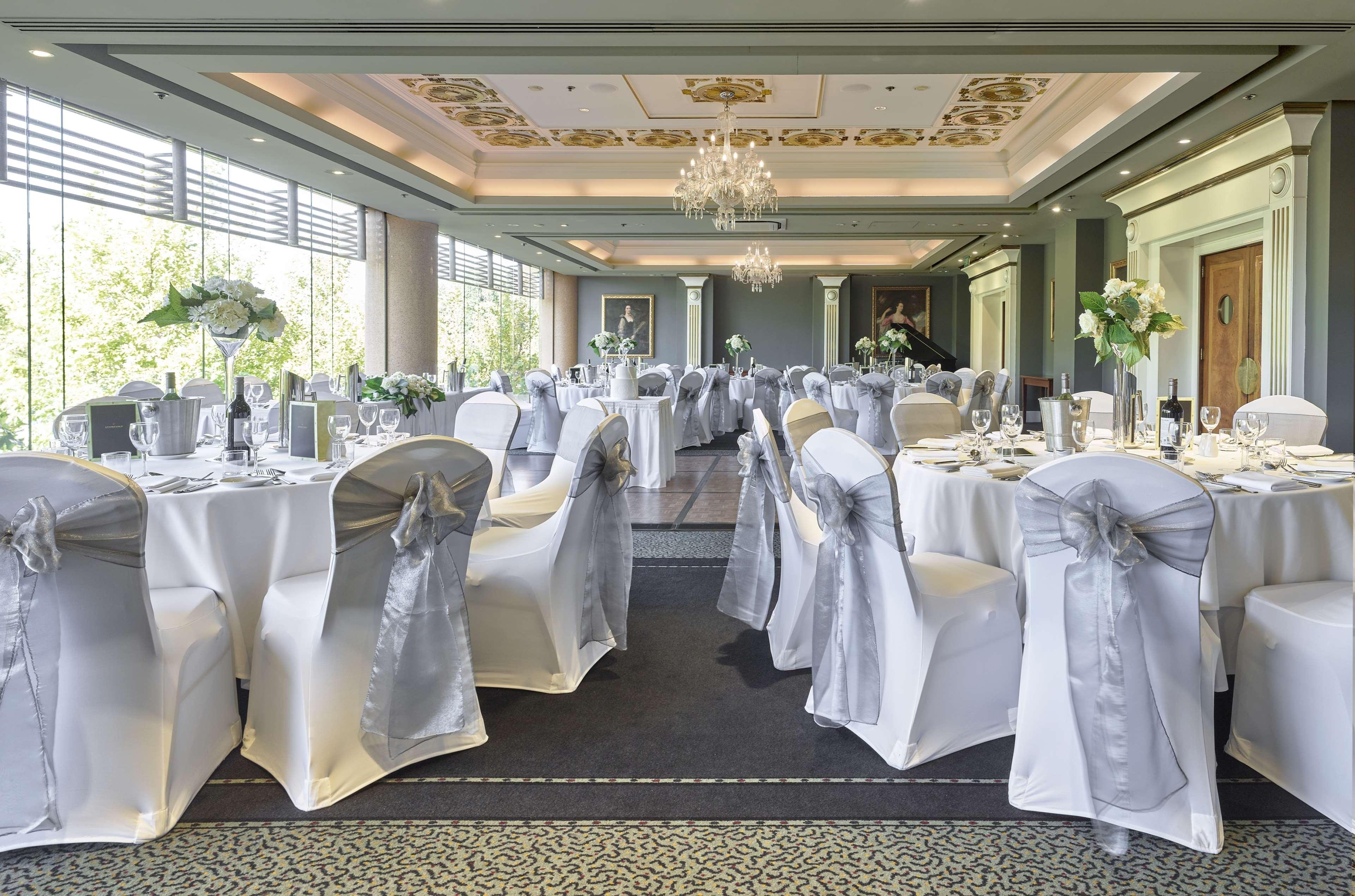 Stamford Plaza Adelaide Hotel ภายนอก รูปภาพ The photo displays an elegantly arranged banquet hall. The room features several round tables covered with white tablecloths, each adorned with silver sashes on the chairs. There are floral centerpieces, possibly white flowers, on the tables, adding 