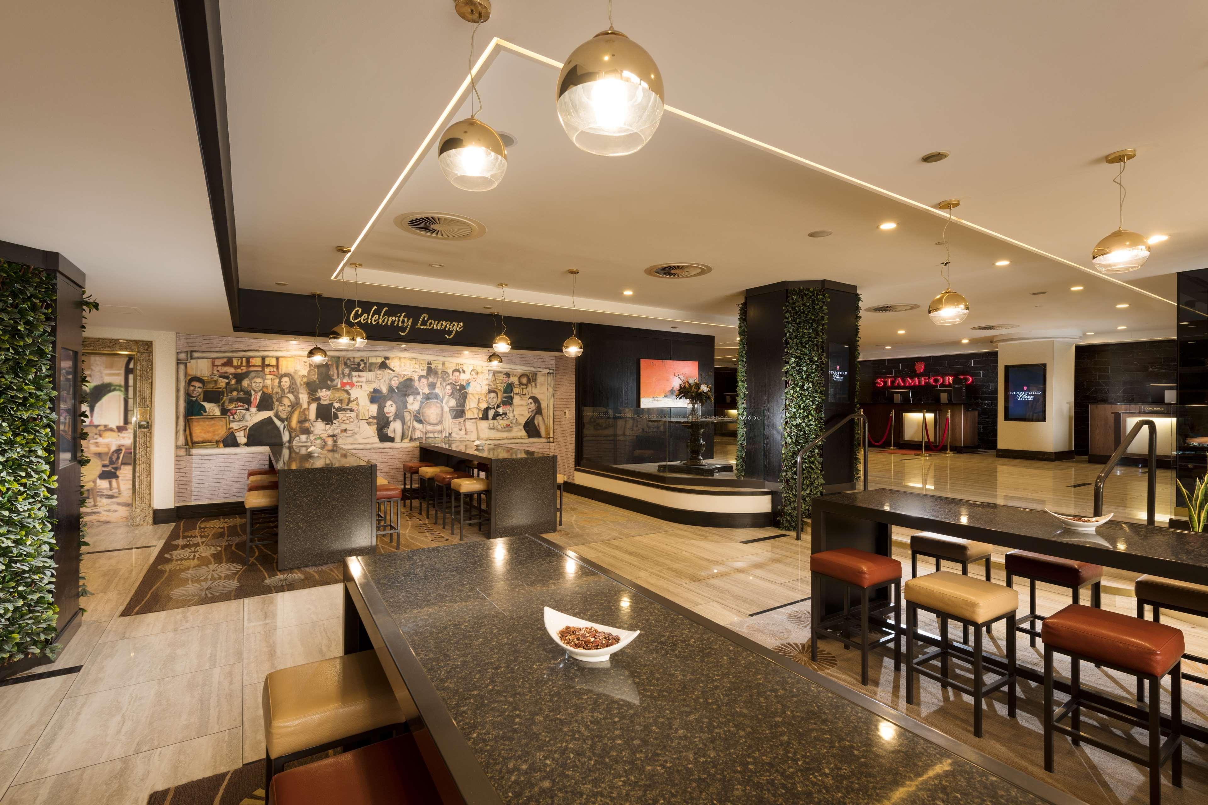 Stamford Plaza Adelaide Hotel ภายนอก รูปภาพ The photo shows a modern and stylish interior of a lounge or restaurant area. Prominent features include a long dark countertop with bar stools, and several pendant lights hanging from the ceiling. In the background, there is a mural or artwork that 